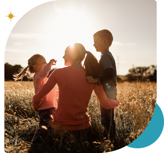 Mom and two children in a field with the sun shining
